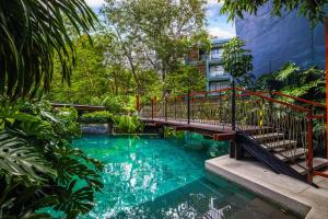 un puente sobre una piscina con árboles y un edificio en 普吉岛自然-YYC旅游优选酒店 Phuket Nature-YYC Travel Preferred Hotel, en Patong Beach