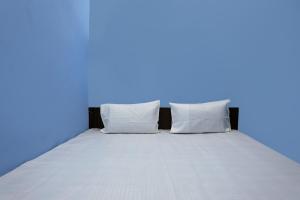 a bed in a blue room with two pillows at OYO HOTEL RELAX in Ballabgarh