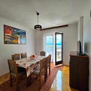 a dining room with a table and chairs and a television at Apartman Agava in Njivice