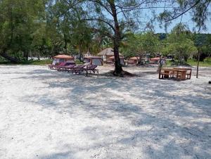 a group of picnic tables sitting under a tree at JIJI KOH RONG in Kaôh Rŭng (3)