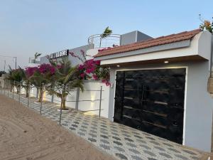 een witte garage met een zwarte deur en een aantal planten bij Sall Residence Saly Appartement 2 in Malikounda Sas