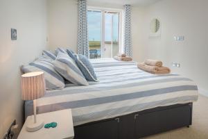 Schlafzimmer mit einem großen Bett mit blauer und weißer Bettwäsche in der Unterkunft 2 Ocean's Edge in Hope-Cove