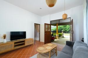 a living room with a couch and a tv at The Orange Villa Near Beach 海灘附近的家庭別墅 in Kamala Beach