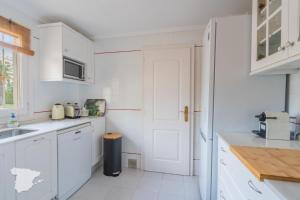 a kitchen with white cabinets and a white door at Apartamento Margarita in Aduanas