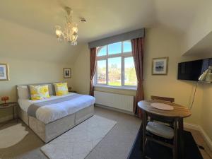 Schlafzimmer mit einem Bett, einem Fenster und einem Tisch in der Unterkunft Melbury Rooms & Studios in Exeter