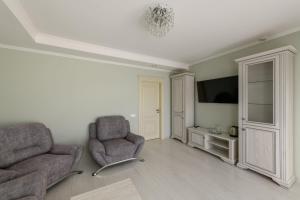 ein Wohnzimmer mit zwei Sesseln und einem Fernseher in der Unterkunft Sagora Hotel in Czernowitz