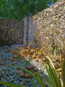 a stone wall with a waterfall in a garden at Dune Alaya Ecolodge in Pemuteran