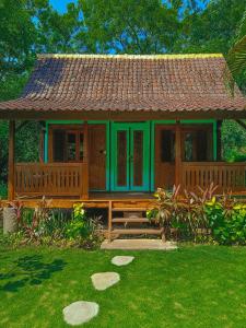 a small house with a large deck in a yard at Dune Alaya Ecolodge in Pemuteran