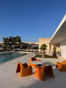 une terrasse avec des chaises orange, une table et une piscine dans l'établissement Villa Nausikaa Essaouira, Villa d'architecte luxe avec piscine, à Essaouira