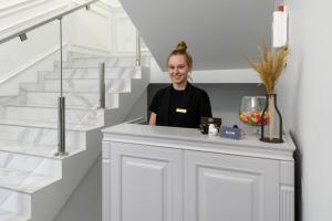 a woman standing behind a counter in a room with stairs at Sagora Hotel in Chernivtsi