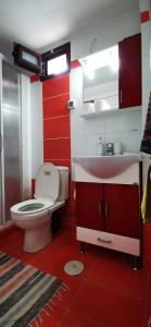a red and white bathroom with a toilet and a sink at Elia Guesthouse in Kissamos