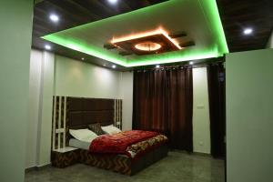 een slaapkamer met een bed met groene verlichting bij Eva Home Stay in Dalhousie