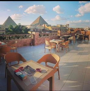 a patio with tables and chairs with pyramids in the background at Pyramids Express View HoTeL in Cairo