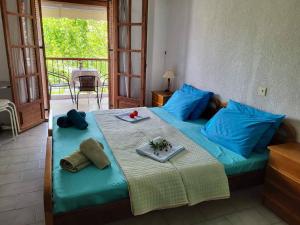 Un dormitorio con una cama con almohadas azules y una mesa. en HOTEL AGNI -ENOIKIAZOMENA DIAMERIZMATA, en Kallithea Halkidikis