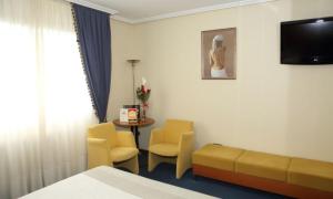 um quarto de hotel com um sofá, cadeiras e uma mesa em Motel Punta Cana em Santiago de Compostela