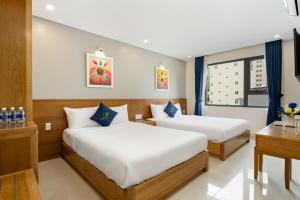 a hotel room with two beds and a desk at CODI SEA Hotel & Travel in Da Nang