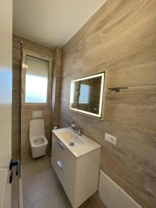 La salle de bains est pourvue de toilettes, d'un lavabo et d'un miroir. dans l'établissement Sunset Sea View - Premium Apartment 2BR, à Durrës