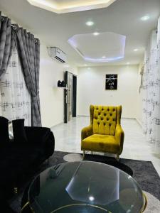 een woonkamer met een gele stoel en een glazen tafel bij Sall Residence Mbour, Appartement 3 in Mbour