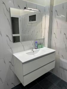 a white bathroom with a sink and a mirror at Sall Residence Mbour, Appartement 3 in Mbour
