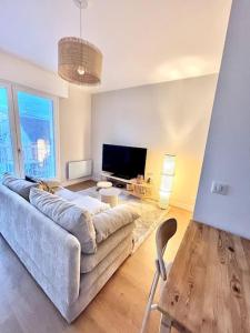 uma sala de estar com um sofá e uma televisão em Appartement avec Balcon et place de Parking à Berck Plage em Berck