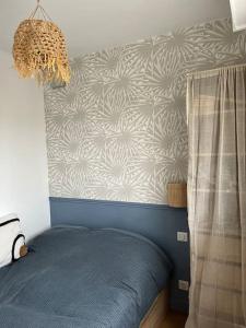 um quarto com uma cama azul e uma parede em Appartement avec Balcon et place de Parking à Berck Plage em Berck