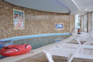 a swimming pool with white chairs and a red raft at Lavender Residence in Kusadası