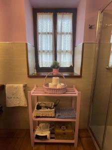 a pink bathroom with a shelf and a window at La Casina de Mon in Quintana de Llanes