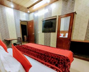 a bedroom with a bed with a red blanket on it at Hotel Grand in Zirakpur