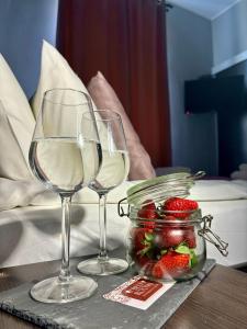 two wine glasses and a jar of strawberries on a table at BedRooms Piotrkowska 64 in Łódź
