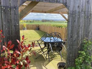 a table and chair sitting under a wooden pergola at High Oak Holiday Cottage in Thirsk