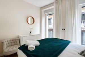 1 dormitorio con 1 cama, 1 silla y ventanas en TuApartamento - Boutique Plaza del Castillo 29, en Pamplona