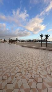 a tiled sidewalk next to a beach with palm trees at ALISA COSTA BLANCA in Platja de l'Arenal