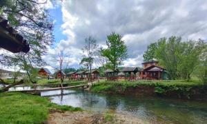 un groupe de maisons près d'une rivière dans l'établissement Bungalow Fly Fishing Kljuc River Sanica, à Zolaći