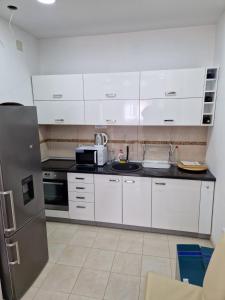 eine Küche mit weißen Schränken, einer Spüle und einem Kühlschrank in der Unterkunft Apartman Sonja Trebinje in Trebinje + 77 Fotos