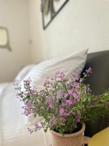 a vase filled with purple flowers next to a bed at Dinka Old Town Apartment in Trogir