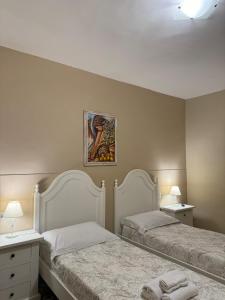 Casa Vacanze Villa Angelina في جيارديني ناكسوس: غرفة نوم بسريرين وطاولتين ومصباحين