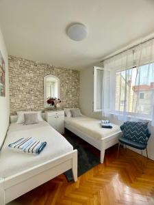 a room with two beds and a chair in it at Dinka Old Town Apartment in Trogir