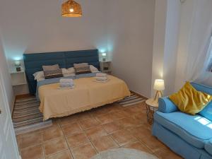 ein Schlafzimmer mit einem Bett und einem blauen Sofa in der Unterkunft casa sierrecilla in Fuente de Piedra