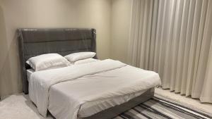 a bed with white sheets and pillows in a bedroom at شقة3 غرف نوم في حي الروضة in Jeddah
