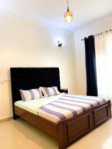 Schlafzimmer mit einem Bett mit einem schwarzen Kopfteil in der Unterkunft COMFORT B&B in Kigali