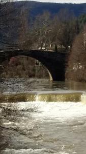 een brug over een rivier met golven in het water bij Le Moulin aux Chandelles, gîtes sans ondes ajoutées ni ajoutables "Le Bois du Sanglier" in Le Vigan