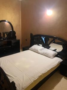 a bedroom with a bed with a black headboard and a mirror at Appartement a loué fes in Fès
