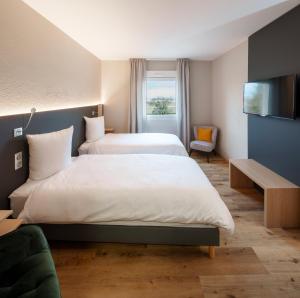 a hotel room with two beds and a television at Logis Hôtel Restaurant Ritter'Hoft in Morsbronn-les-Bains
