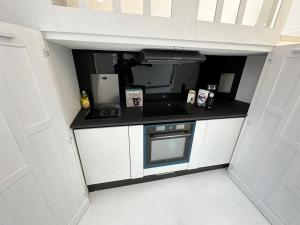 a small kitchen with white cabinets and a stove at Nice flat near Church Street in London