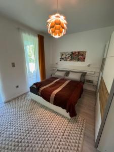 1 dormitorio con cama y lámpara de araña en Fűzliget2-Mistral Garden, en Balatonfűzfő