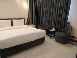 een hotelkamer met een bed en twee stoelen bij Panorama Guest House in Islamabad