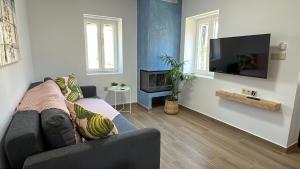 sala de estar con sofá y TV de pantalla plana en Nafsika Stone Apartment en Lazaráta