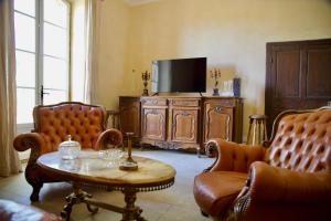 ein Wohnzimmer mit einem TV, einem Tisch und Stühlen in der Unterkunft Château de Sienne proche Avignon Orange 7 Chambres Piscine Rivière in Chusclan