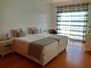 um quarto com uma cama grande e uma janela grande em Casa dos Medros em São Martinho do Porto