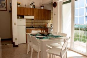 une cuisine avec une table blanche avec des chaises et une fenêtre dans l'établissement Villa Isolda: moderno trilocale, à Bibione